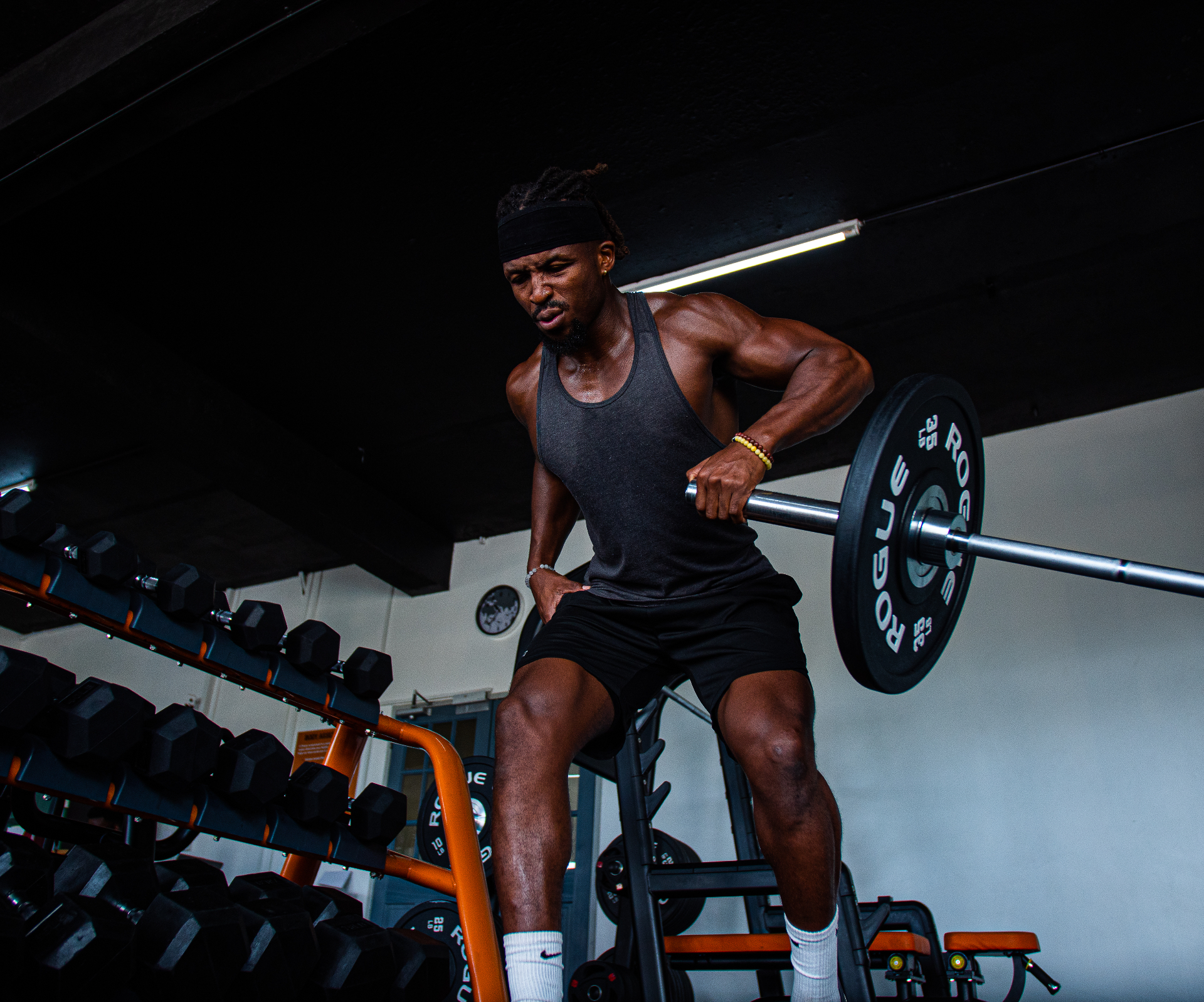 Athlete training with a barbell in a dark gym